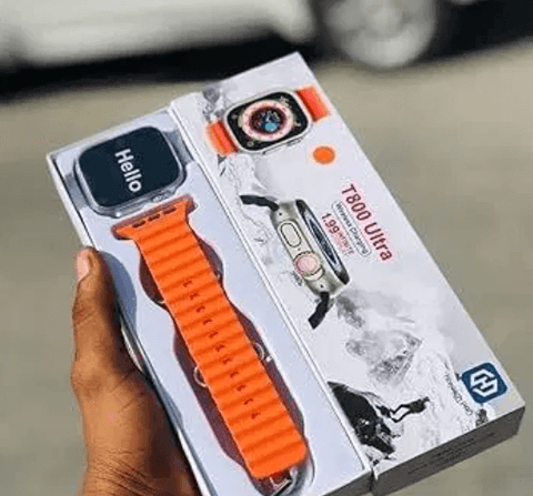 Hand holding T800 Ultra smartwatch with orange band and box, outdoor background