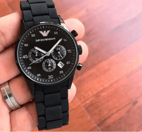 Black men's chronograph wristwatch with black ceramic band held in hand, luxury timepiece
