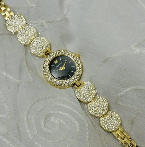 Gold ladies wristwatch with black dial and crystal-studded round links on white fabric