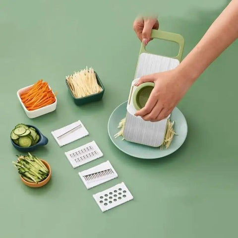 Multi-blade vegetable slicer in use with sliced carrots, cucumbers, and julienned vegetables on a green background.
