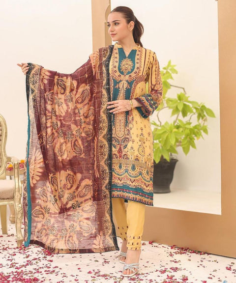 Woman in a yellow embroidered salwar kameez with printed dupatta, standing indoors