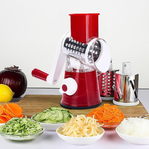 Rotary vegetable slicer with red handle surrounded by sliced carrots, cucumbers, and onions